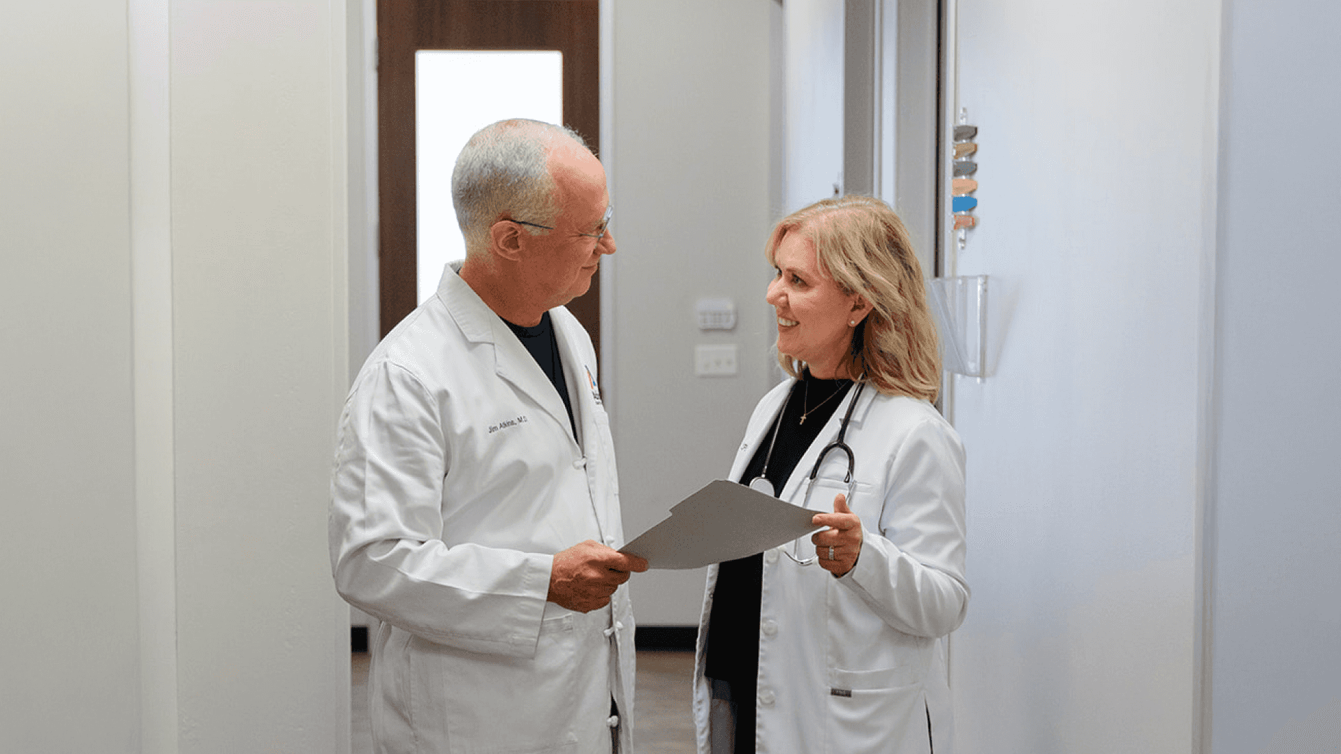 Two doctors in white coats speaking to each other.